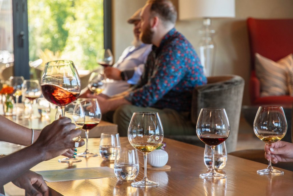 A group of people enjoys wine tasting in a cozy, sunlit room with large windows in Healdsburg, California.