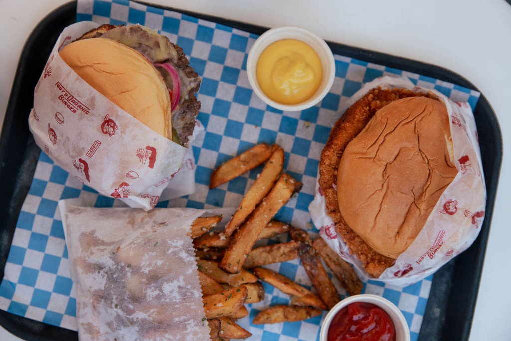 A tray holds three burgers wrapped in paper, a side of fries, and condiment cups in Healdsburg, California.