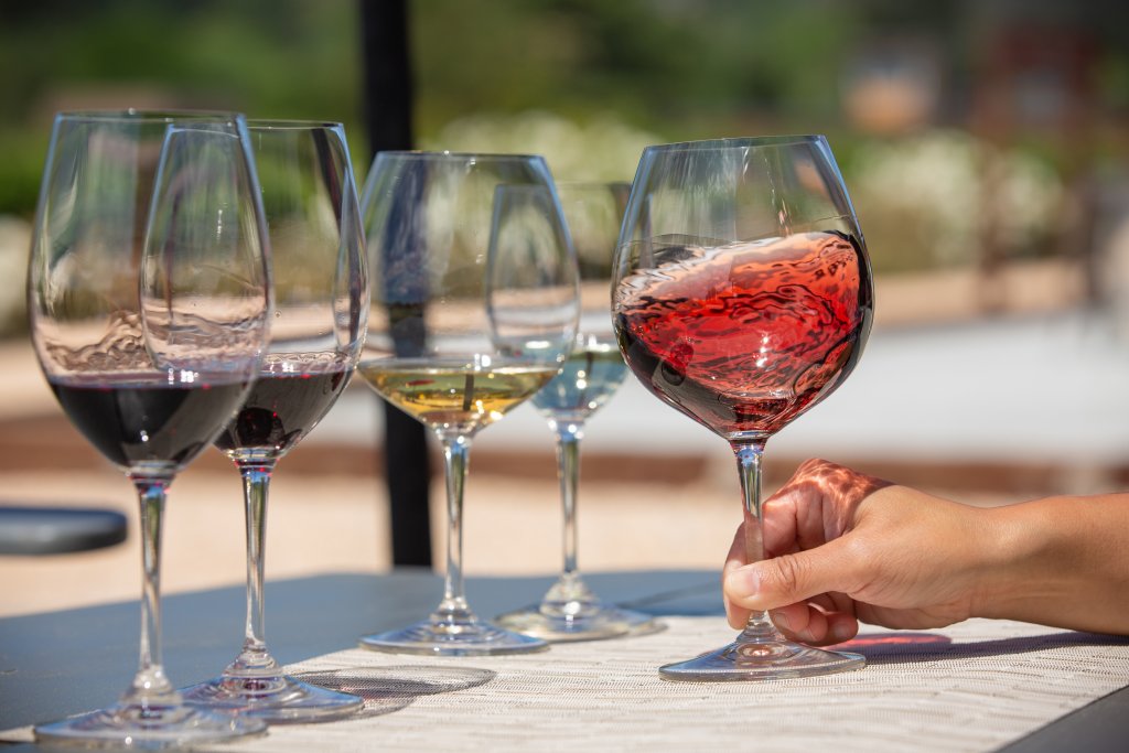 A hand holds a glass of red wine among five other wine glasses on a table in Healdsburg, California.