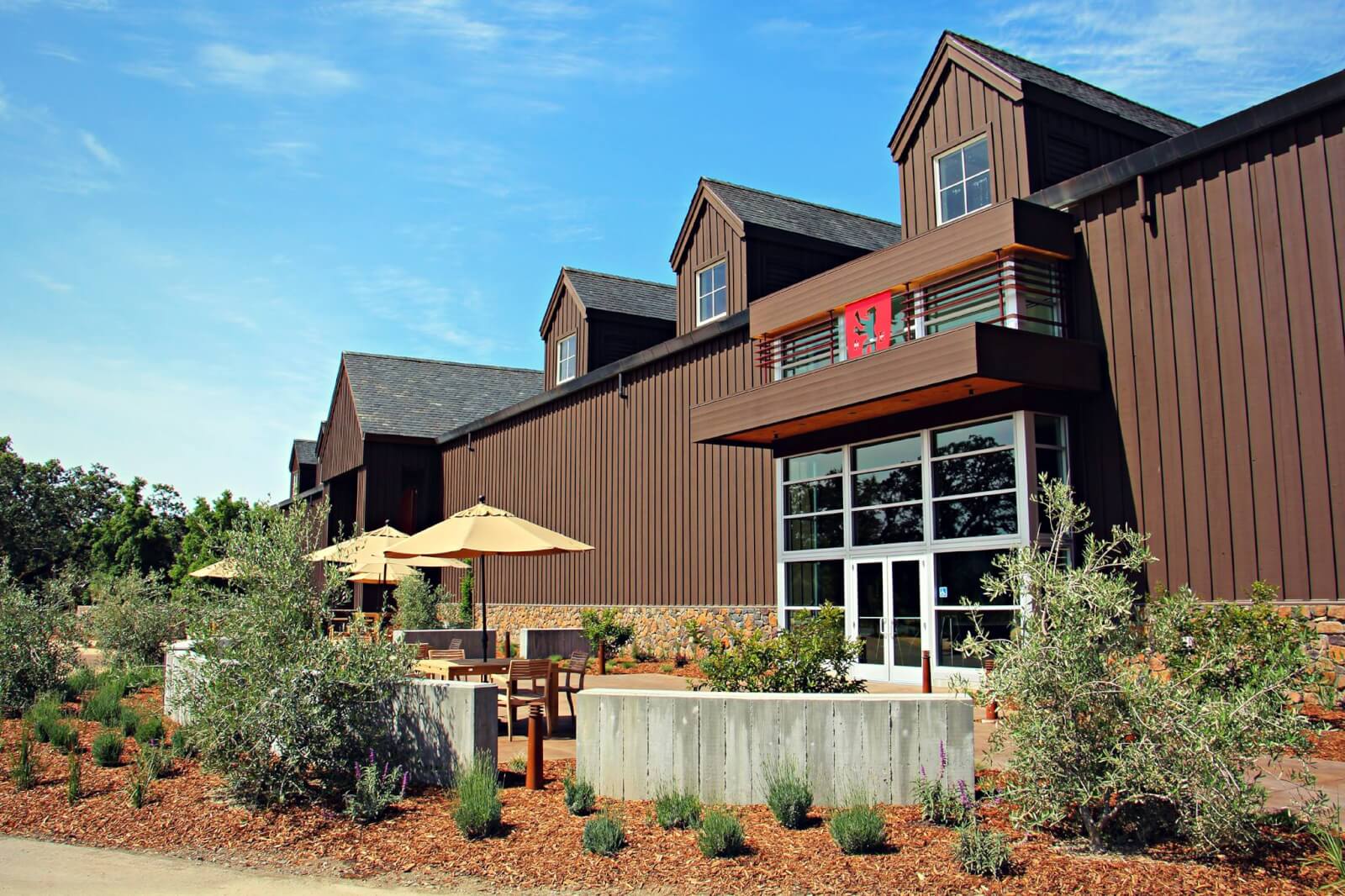 A modern wooden building with large windows and a patio area surrounded by greenery in Healdsburg, California.