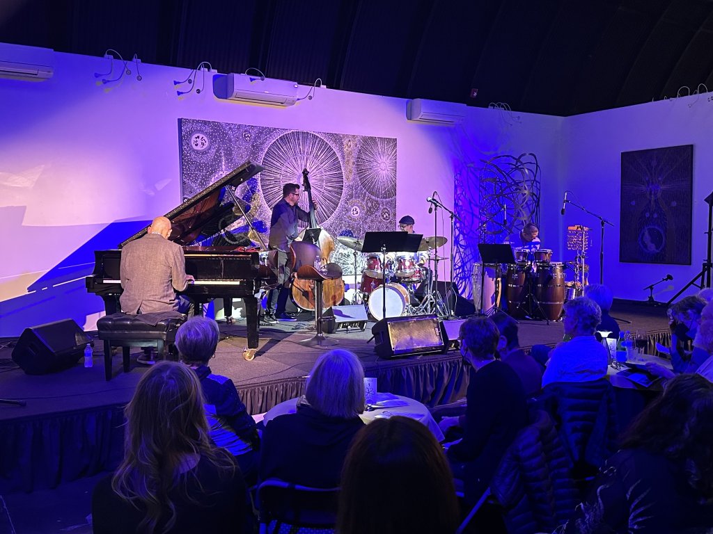 A jazz band performs on a stage with a pianist, bassist, drummer, and guitarist in Healdsburg, California.