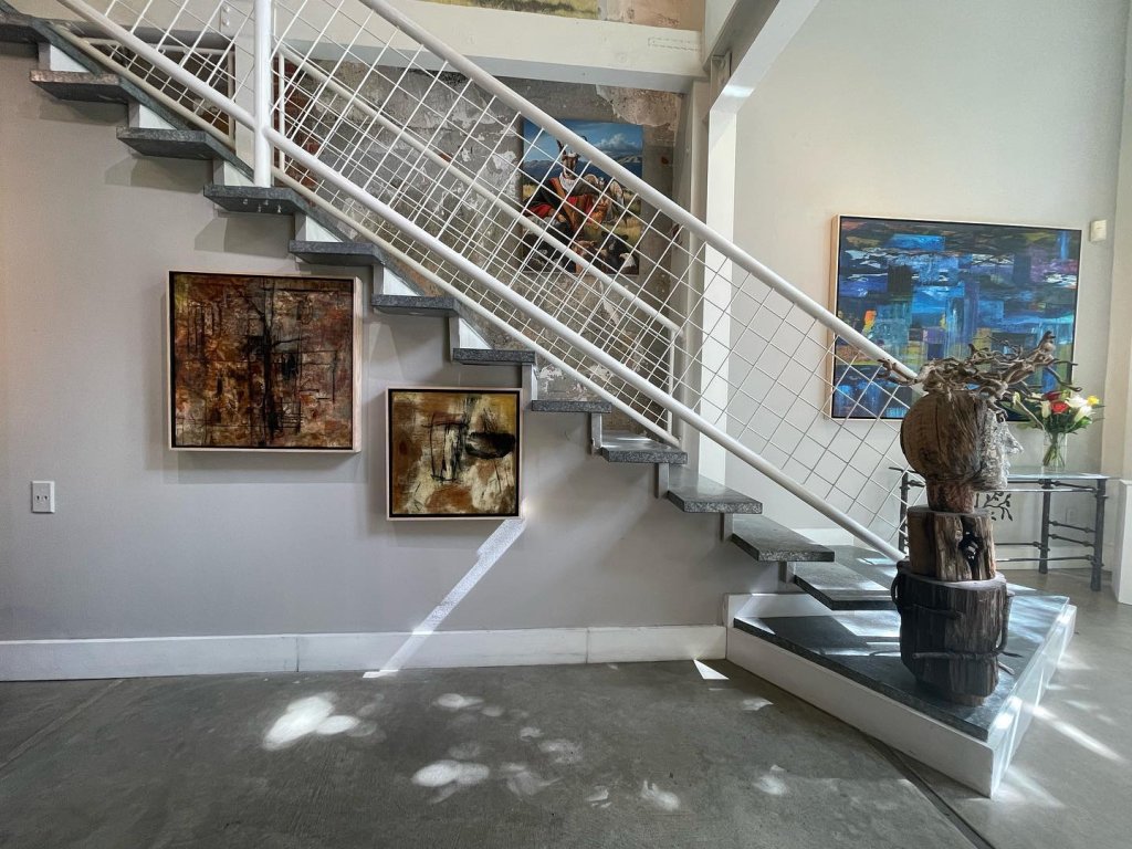 A modern staircase with a white metal railing leads up to a gallery-like space with abstract art on the walls in Healdsburg, California.