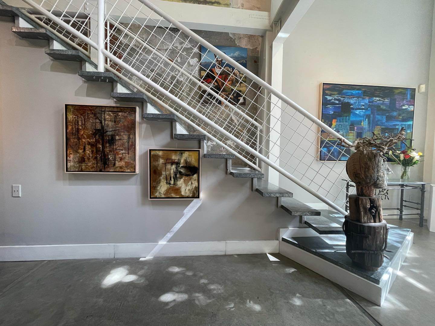 Erickson Fine Art Gallery, Inc. A modern staircase with a white metal railing leads up to a gallery-like space with abstract art on the walls in Healdsburg, California.