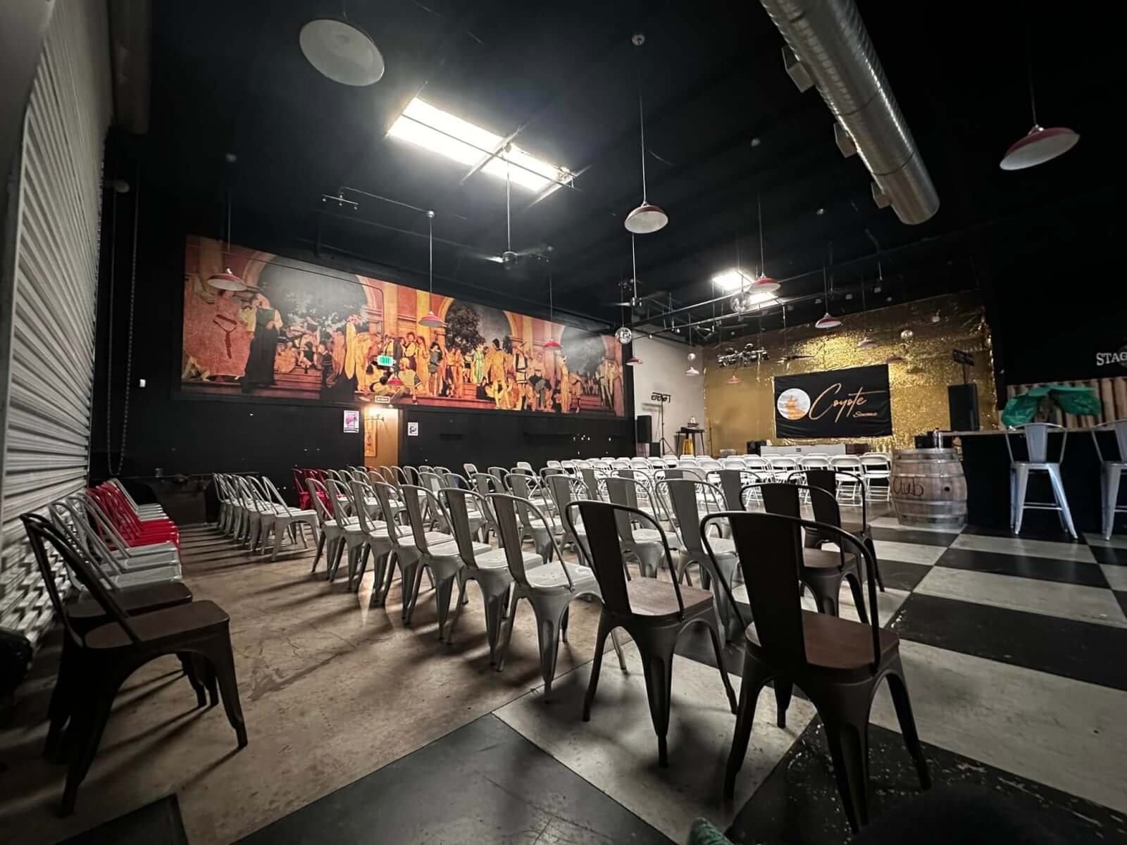 A spacious room with rows of metal chairs, a stage, and a large mural on the wall in Healdsburg, California.