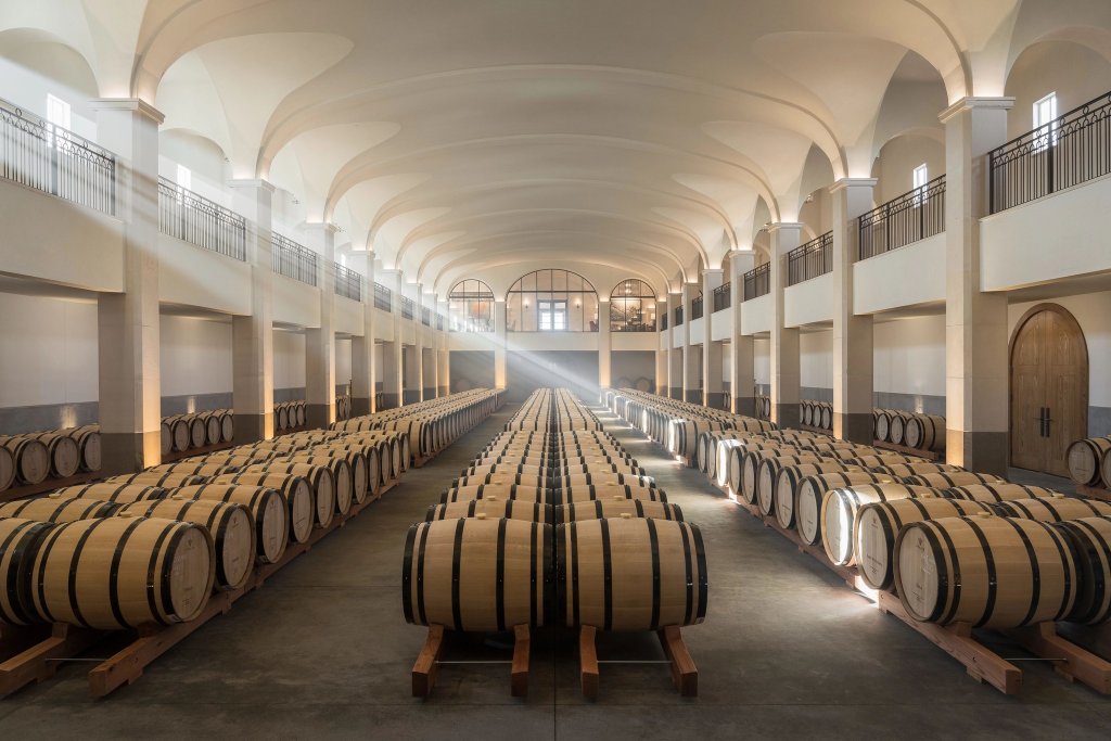 A vast wine cellar with rows of wooden barrels under a high arched ceiling in Healdsburg, California.