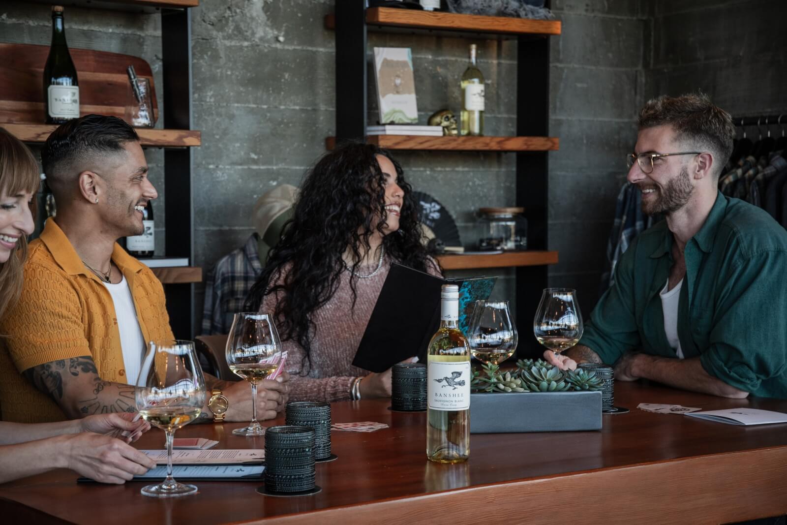 A group of five people enjoying wine and conversation at a rustic wooden table in Healdsburg, California.