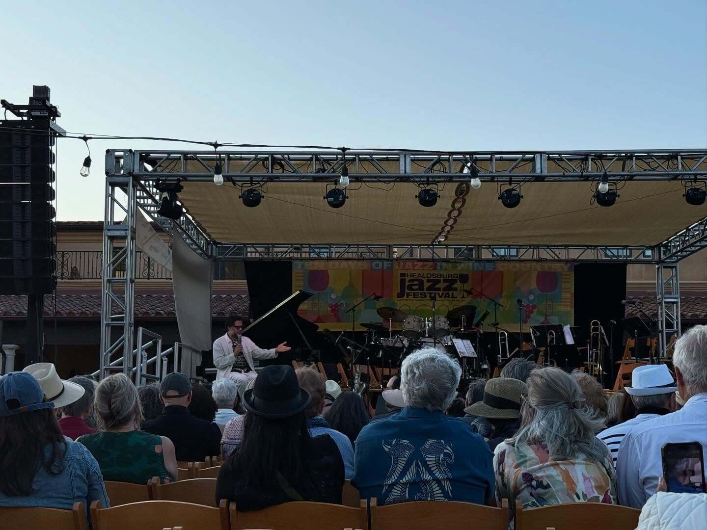 Healdsburg Jazz Outdoor jazz concert with pianist and orchestra on stage, audience seated in rows of chairs in Healdsburg, California.