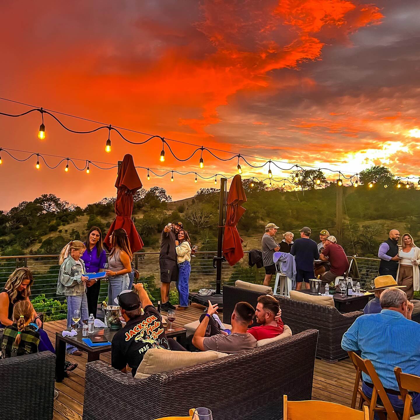 Notre Vue Estate Winery A group of people enjoying a sunset gathering on a rooftop deck with string lights in Healdsburg, California.