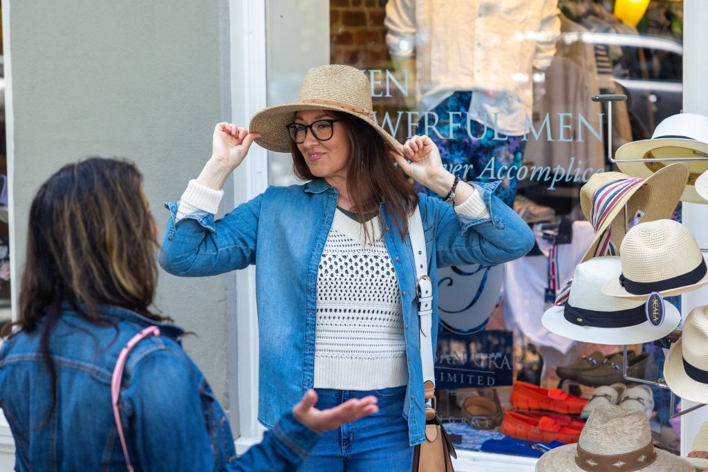 Two women are outside a hat shop, one adjusting her wide-brimmed hat in Healdsburg, California.