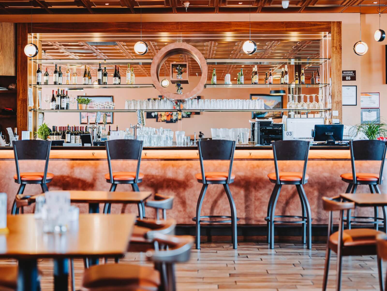 Bollywood Kitchen A modern restaurant bar with wooden decor, orange stools, and a variety of wine bottles displayed in Healdsburg, California.