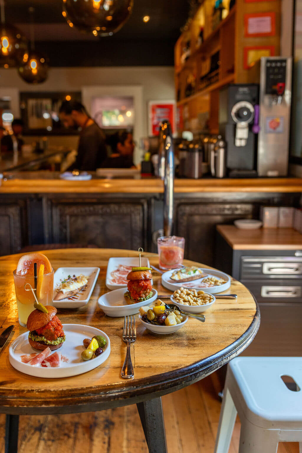 Bravas Bar de Tapas A variety of tapas dishes and drinks are arranged on a wooden table in a cozy restaurant setting in Healdsburg, California.