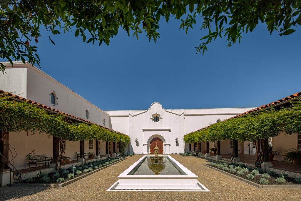 A serene courtyard with a central fountain, surrounded by white buildings and lush greenery in Healdsburg, California.