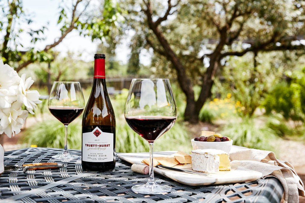 A bottle of Truett-Hurst Pinot Noir with two glasses of red wine on a patio table in Healdsburg, California.