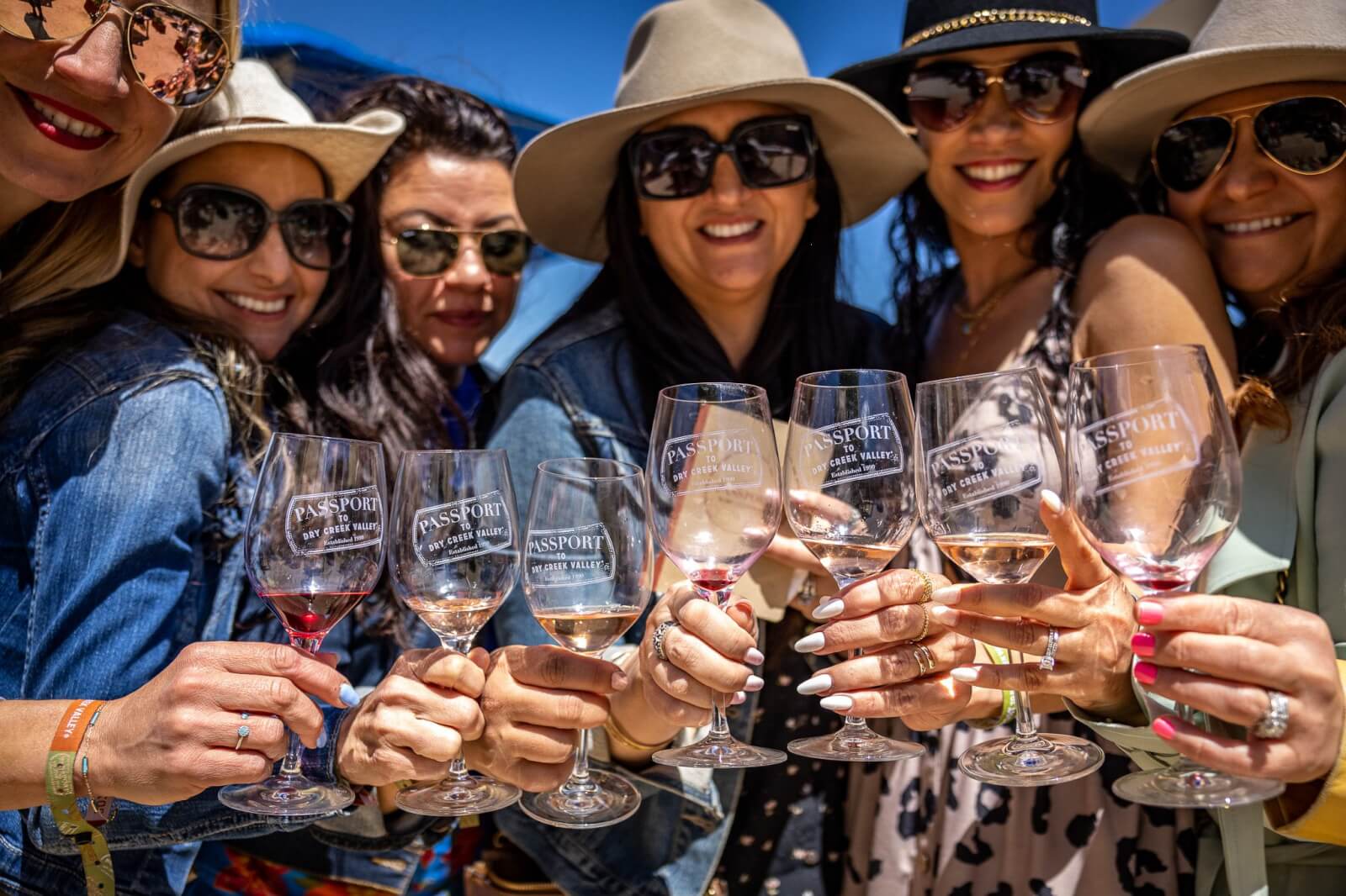 A Healdsburg for All Seasons: Your Guide to Annual Events and Festivals A group of six women, all wearing sunglasses and hats, cheerfully clink wine glasses together outdoors in Healdsburg, California.