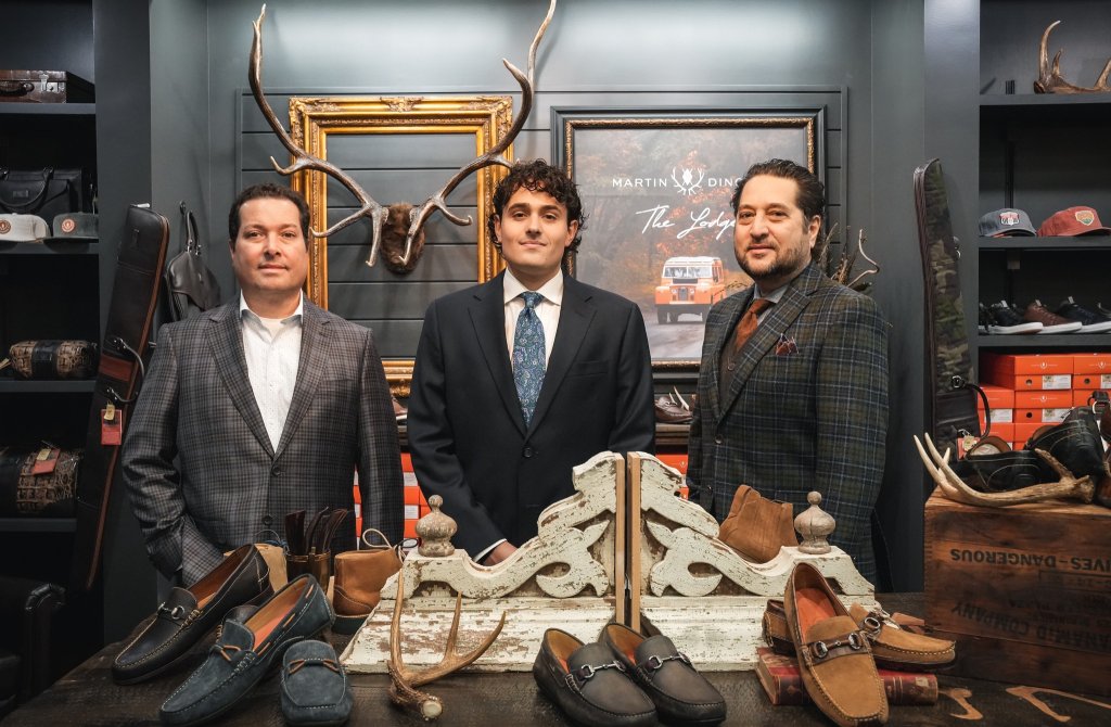 Three men in suits stand behind a table of shoes in a rustic store with antlers and hats in Healdsburg, California.