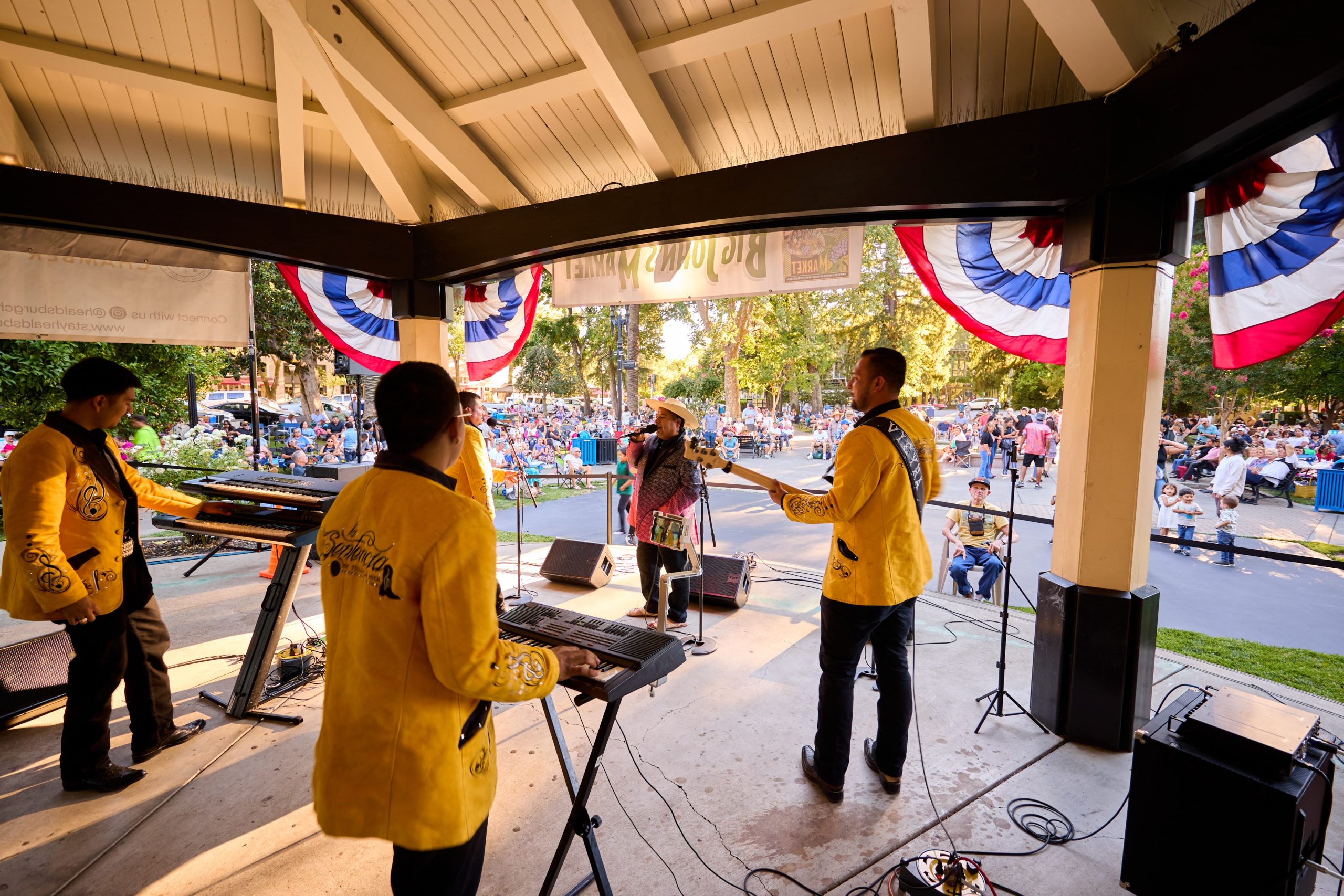 Annual Events & Holidays A mariachi band in yellow jackets performs on a stage at an outdoor festival in Healdsburg, California.