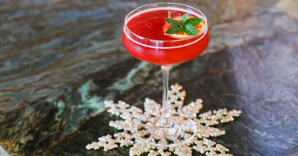 A festive red cocktail garnished with mint and orange slice in a martini glass in Healdsburg, California.