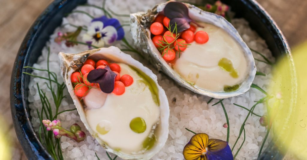 Two oysters on the half shell garnished with red caviar, herbs, and edible flowers in Healdsburg, California.