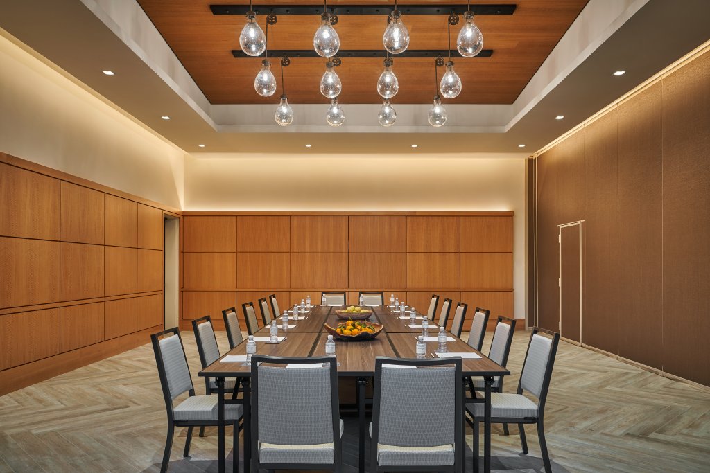 Hogar A modern conference room with a long wooden table, chairs, and hanging light bulbs in Healdsburg, California.