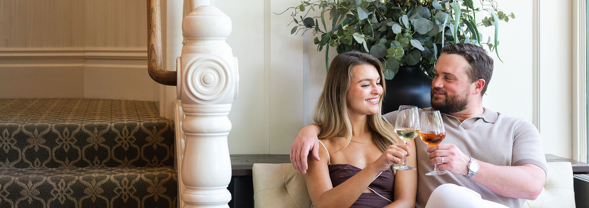 A couple enjoys wine on a couch near a staircase with floral decor in Healdsburg, California.