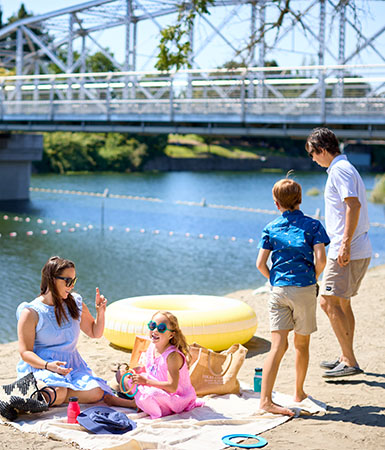 Hogar A family enjoys a sunny day at the beach, with a bridge in the background in Healdsburg, California.