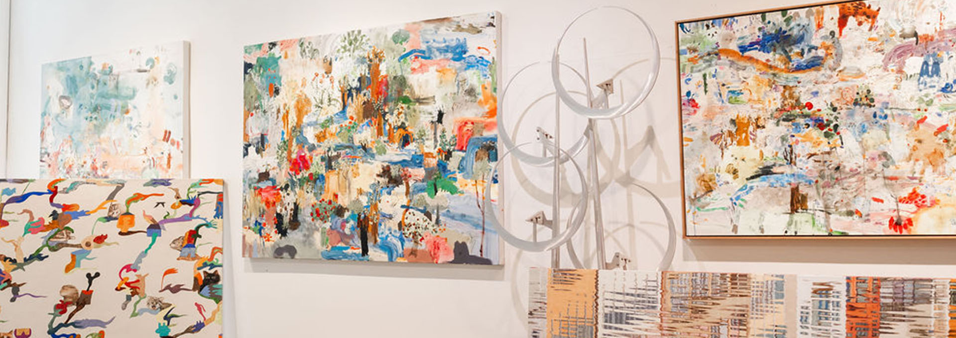 Abstract paintings with vibrant colors and dynamic brushstrokes adorn white walls in Healdsburg, California.