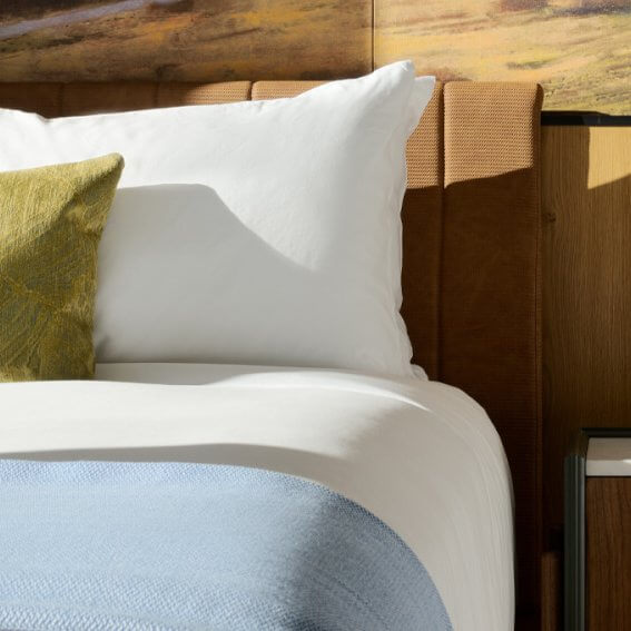 Special Offers A neatly made bed with white pillows, a green throw pillow, and a blue blanket in Healdsburg, California.