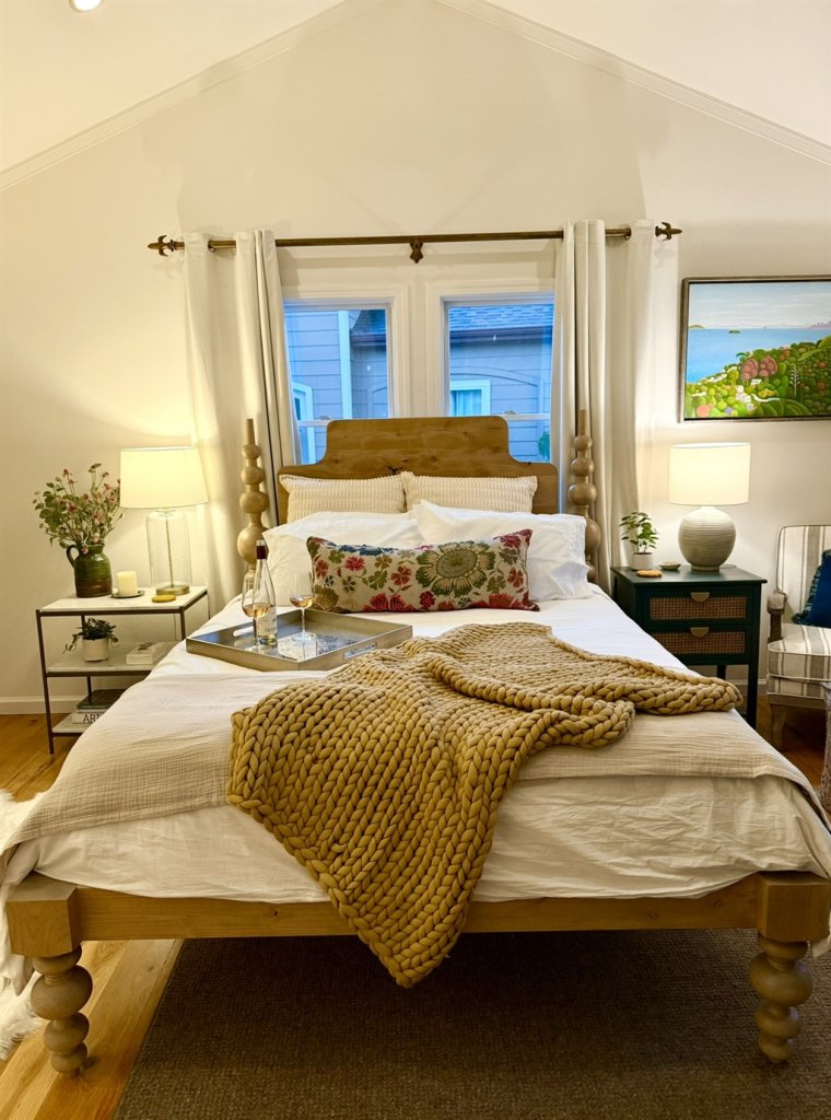 A cozy bedroom with a wooden bed, floral pillows, and a knitted throw blanket in Healdsburg, California.