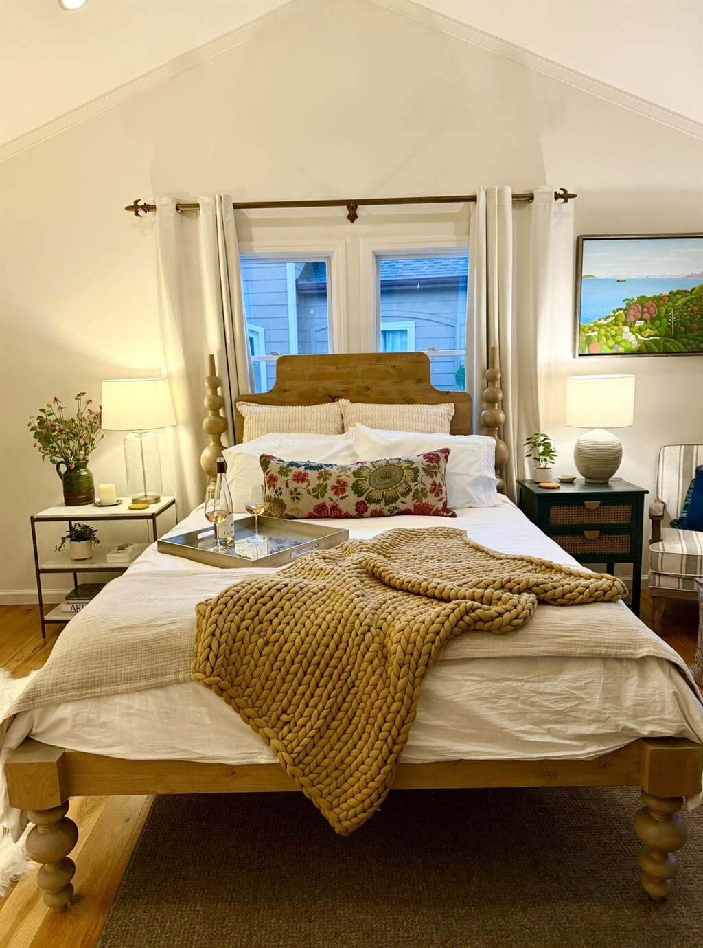 A cozy bedroom with a wooden bed, floral pillows, and a knitted throw blanket in Healdsburg, California.