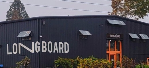 A dark industrial building with 'LONGBOARD' in white letters and an orange door in Healdsburg, California.