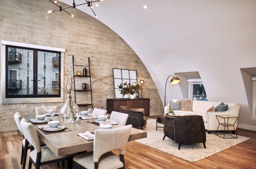 Modern loft with curved ceiling, concrete wall, dining table, and living room area in Healdsburg, California.