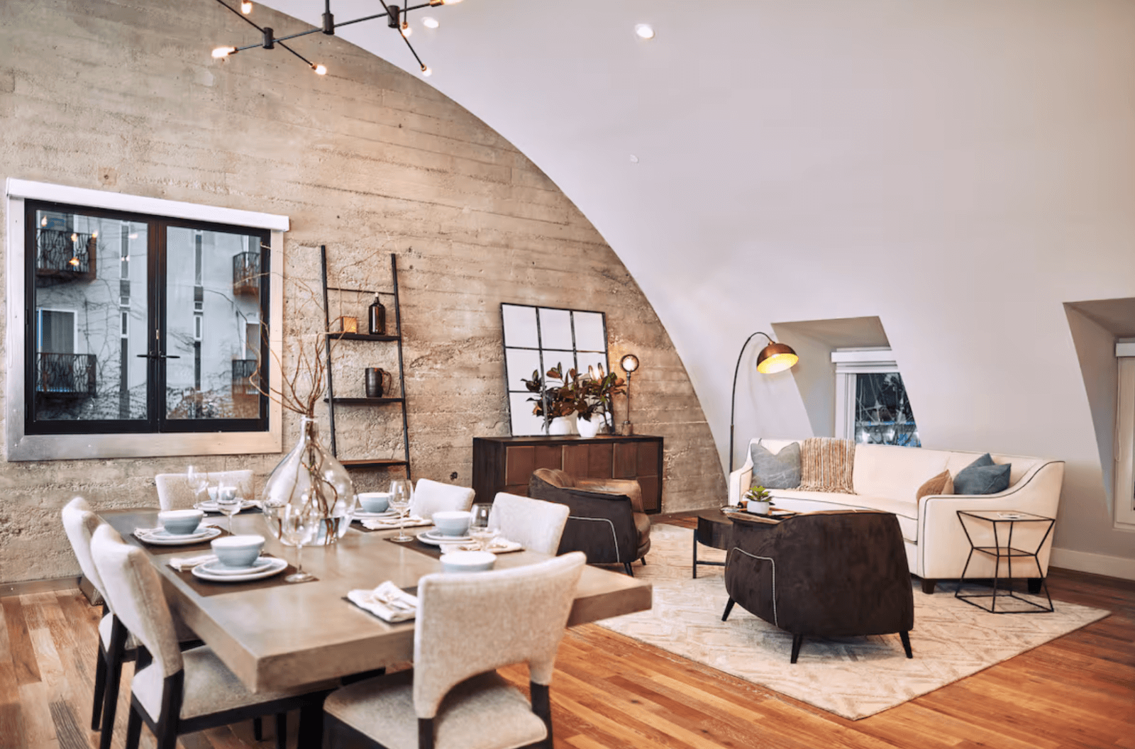 Modern loft with curved ceiling, concrete wall, dining table, and living room area in Healdsburg, California.
