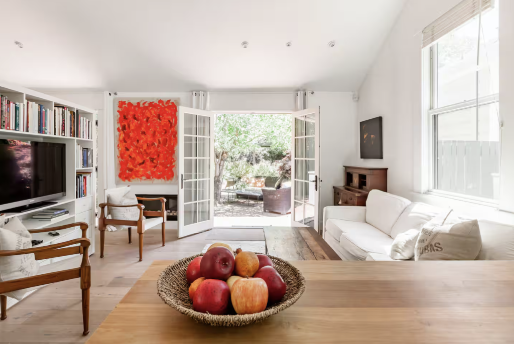 A bright, airy living room with white walls, wooden floors, and a basket of apples on the coffee table in Healdsburg, California.