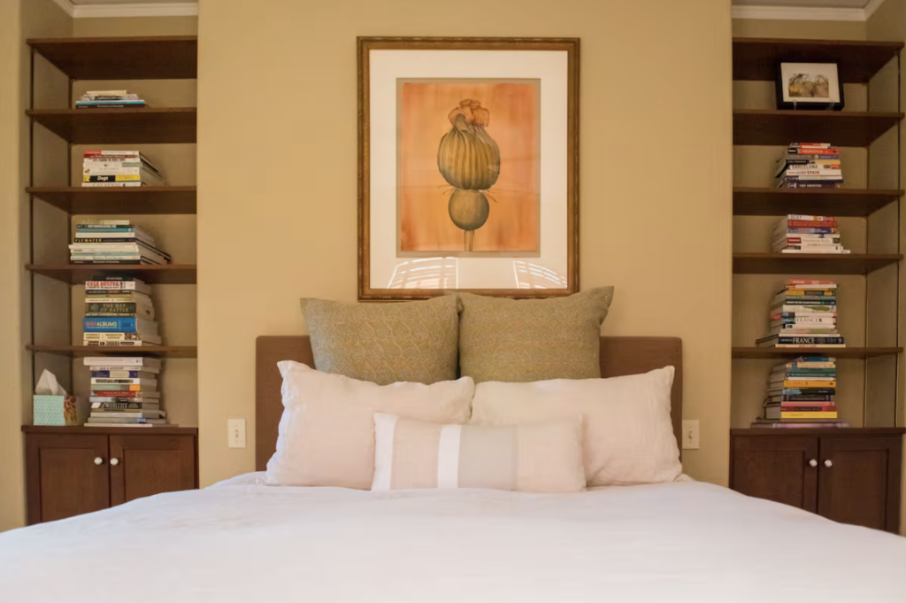 A neatly made bed with white linens and multiple pillows is centered in a room with built-in bookshelves in Healdsburg, California.