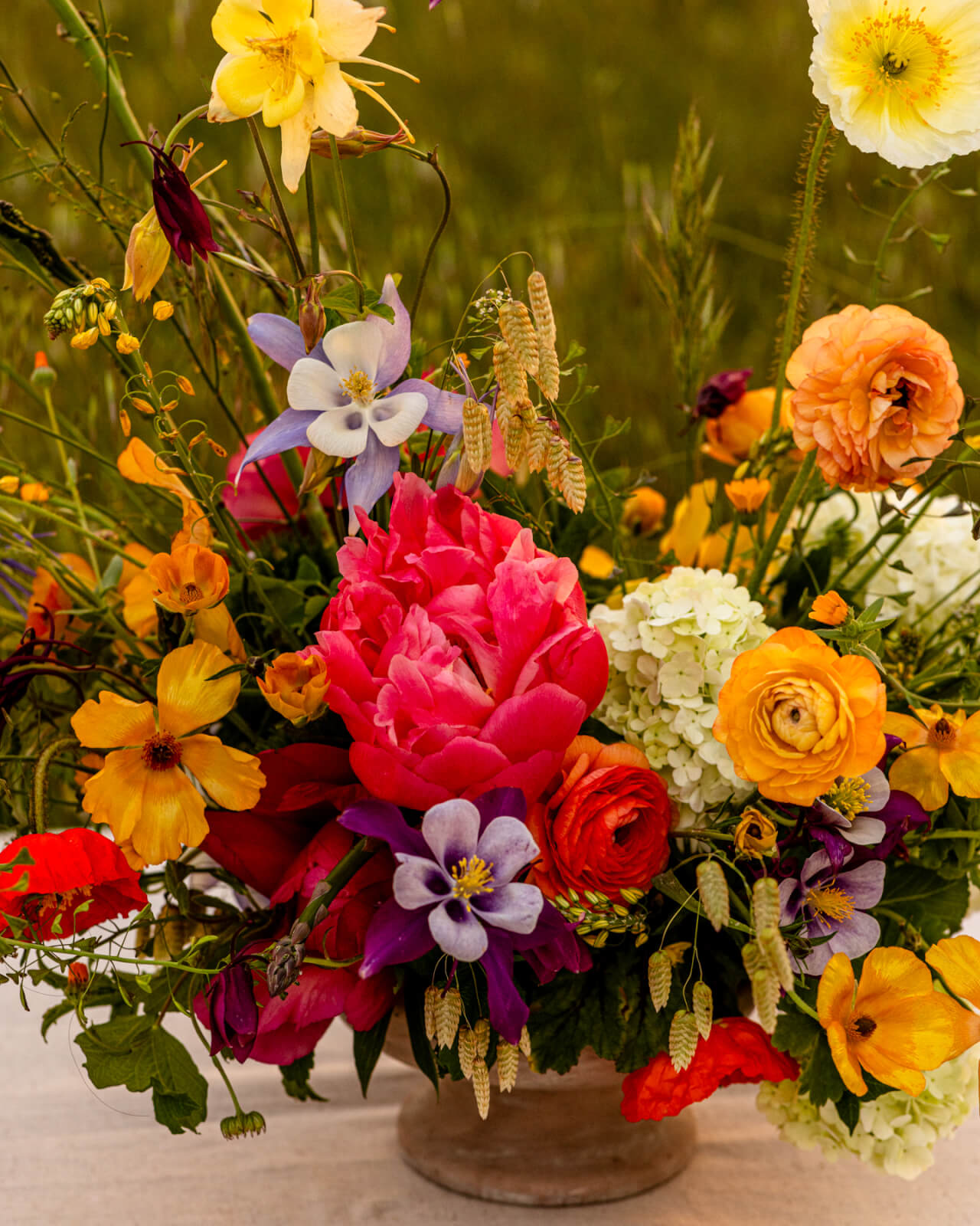 A vibrant bouquet of wildflowers and garden blooms in a variety of colors, including yellow, orange, pink, purple, and white, arranged in a rustic vase in Healdsburg, California.
