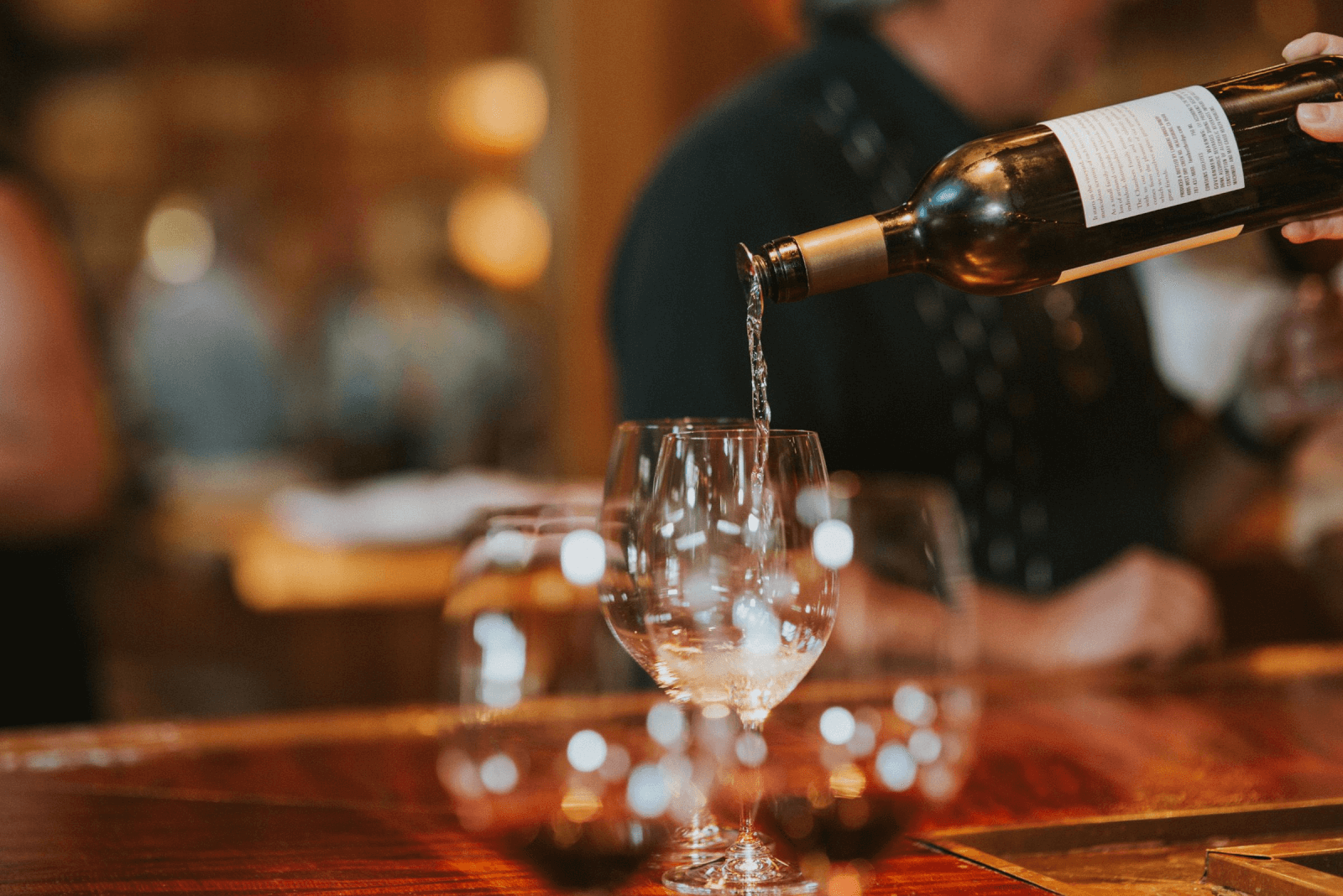 A hand pours white wine from a bottle into a glass at a bar in Healdsburg, California.