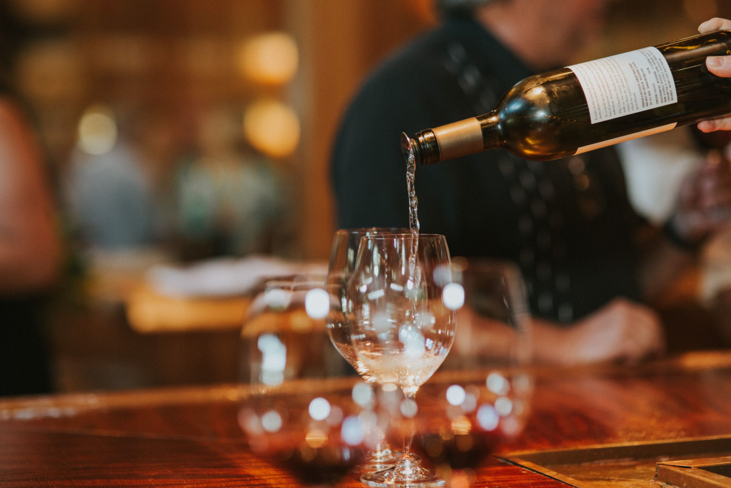 A hand pours white wine from a bottle into a glass at a bar in Healdsburg, California.
