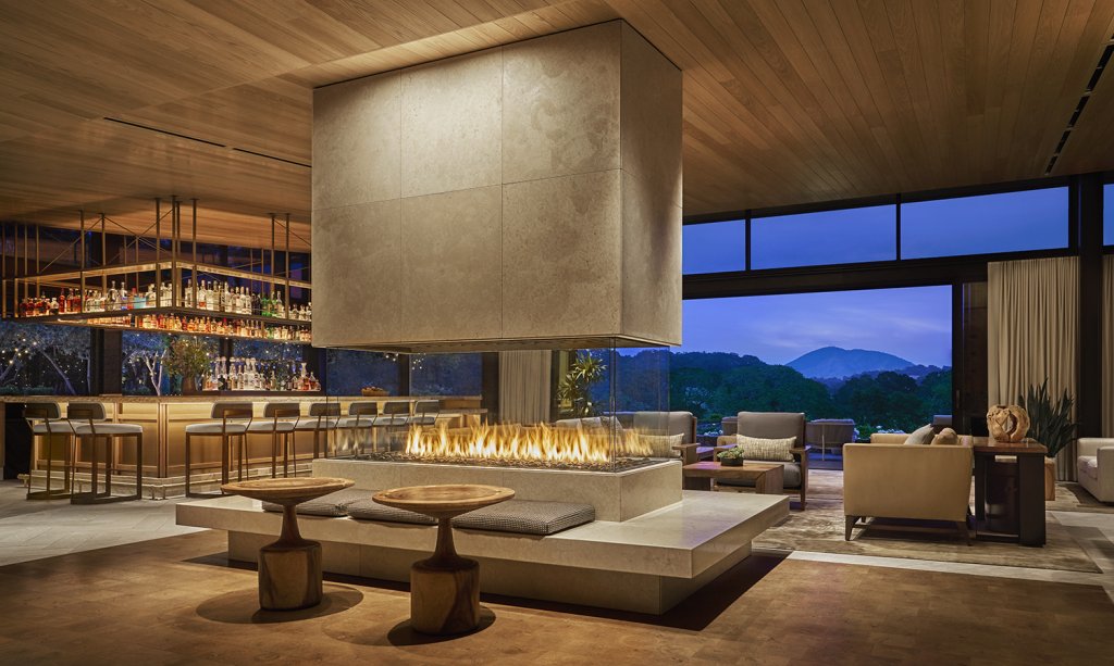 A modern living room with a large fireplace, comfortable seating, and a bar area with a view of the outdoors in Healdsburg, California.