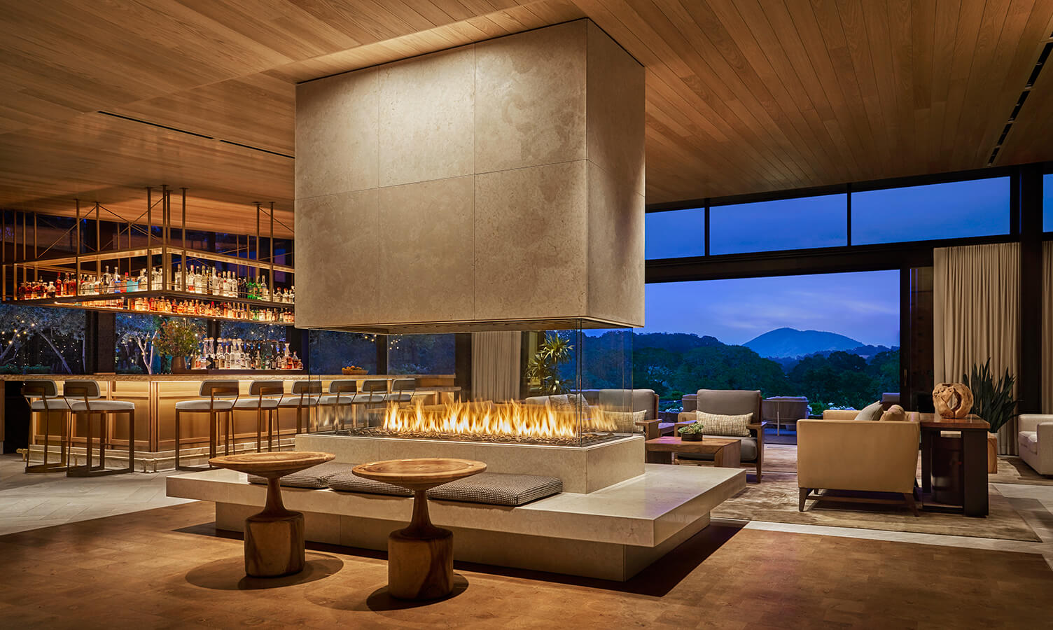 Complimentary 3rd Night at Montage A modern living room with a large fireplace, comfortable seating, and a bar area with a view of the outdoors in Healdsburg, California.