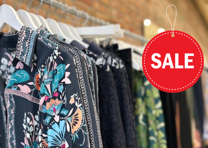 A row of colorful, patterned shirts on hangers with a prominent 'SALE' sign hanging nearby in Healdsburg, California.