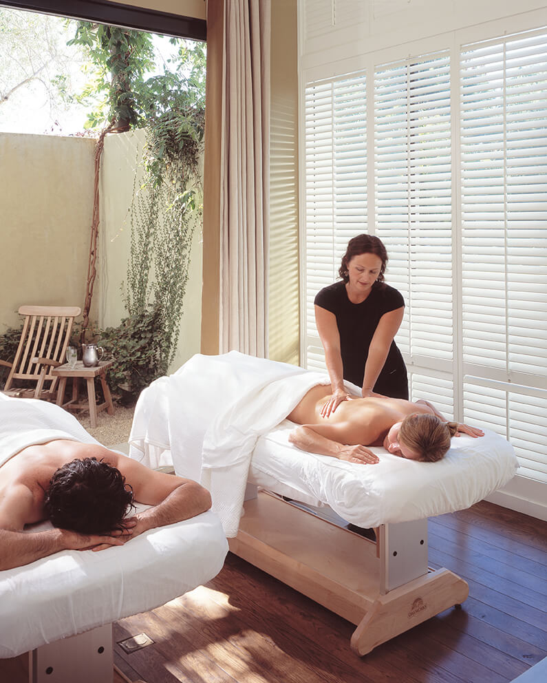 Two couples receive massages in a serene spa setting with natural light and greenery in Healdsburg, California.