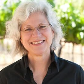 A smiling woman with gray hair and glasses wearing a black shirt outdoors in Healdsburg, California.