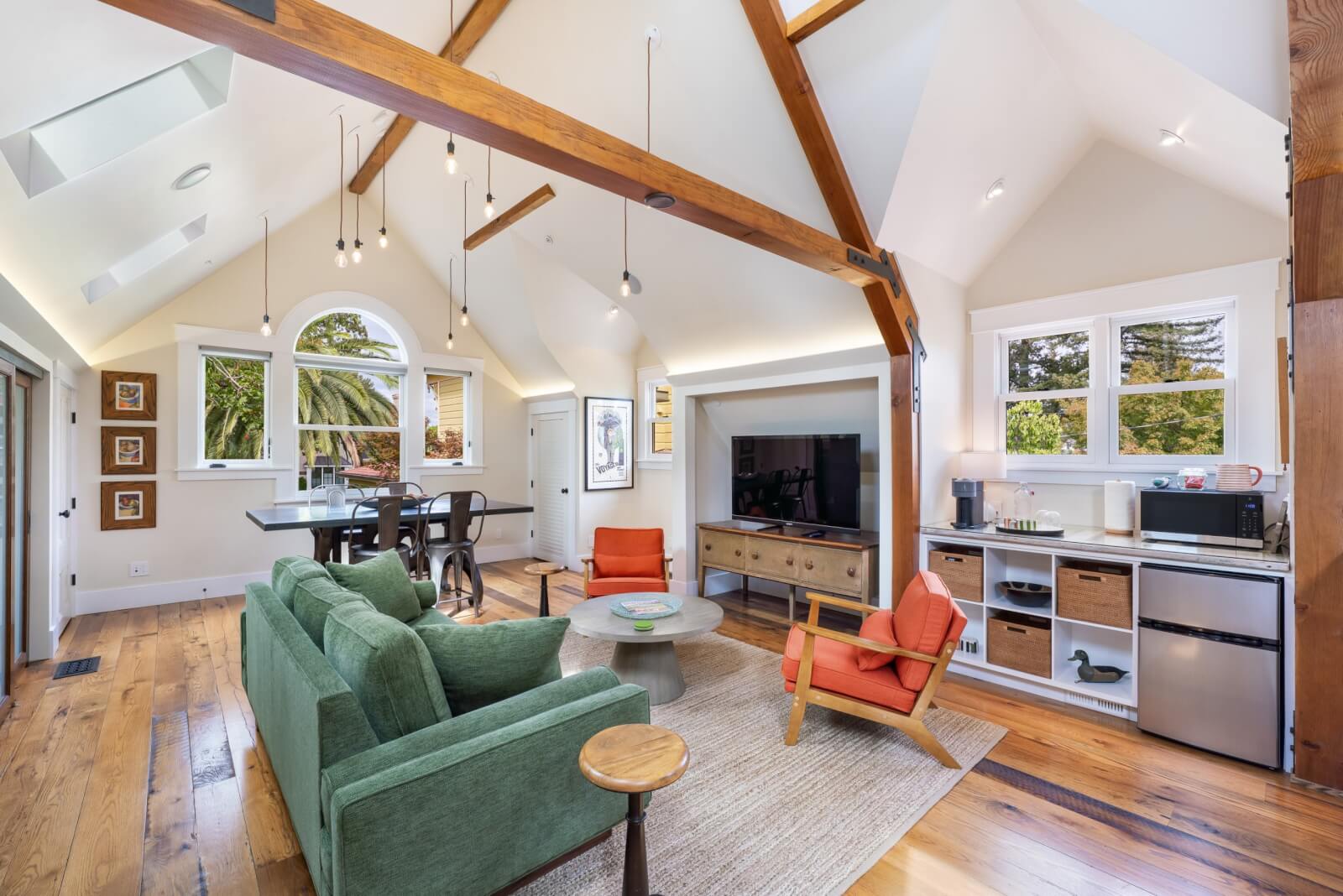 Carriage House Healdsburg A cozy, modern living room with a green sofa, orange chairs, and a dining area featuring a wooden table and chairs in Healdsburg, California.
