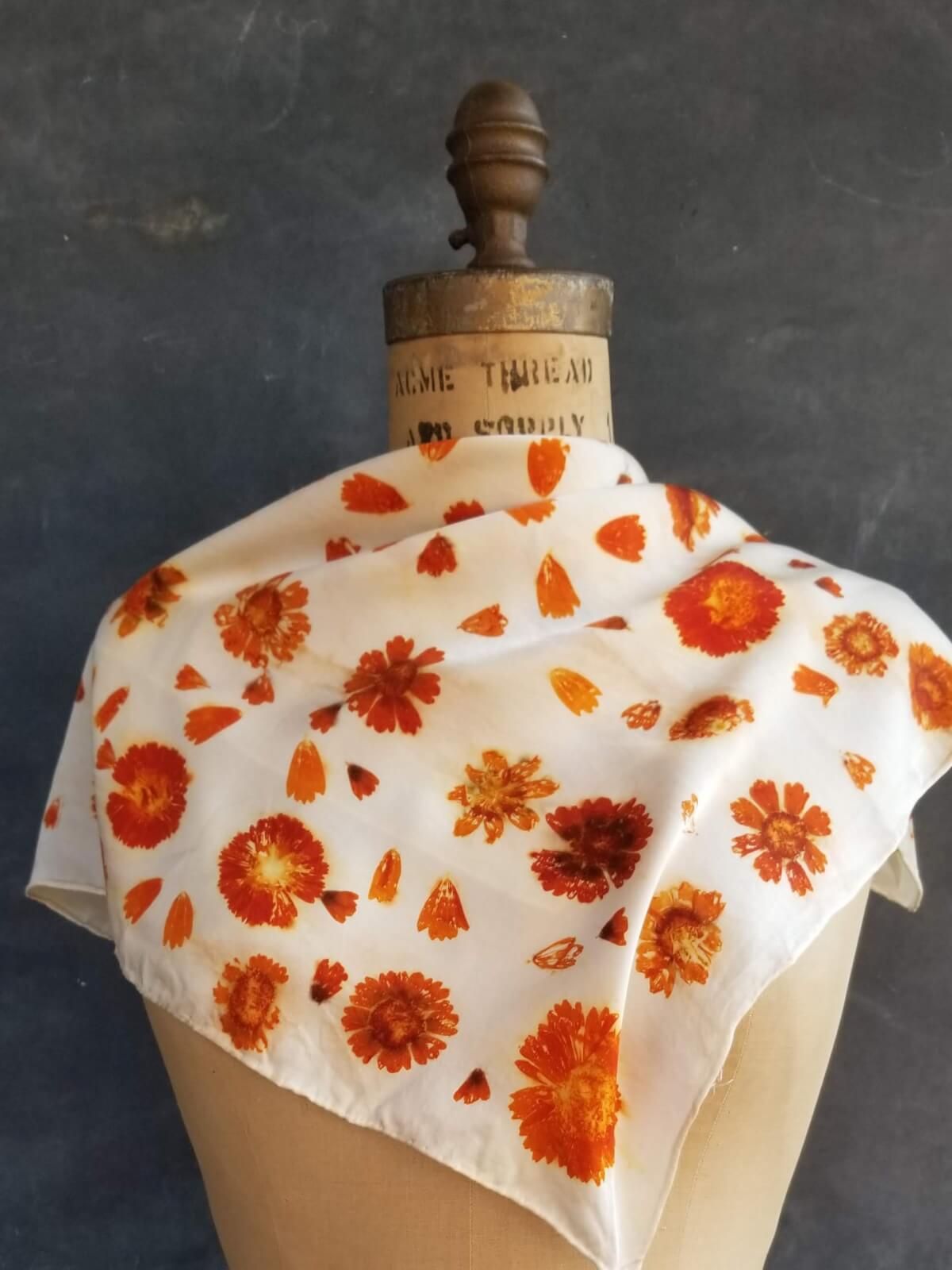 A white silk scarf adorned with vibrant orange floral patterns is draped over a mannequin's neck in Healdsburg, California.