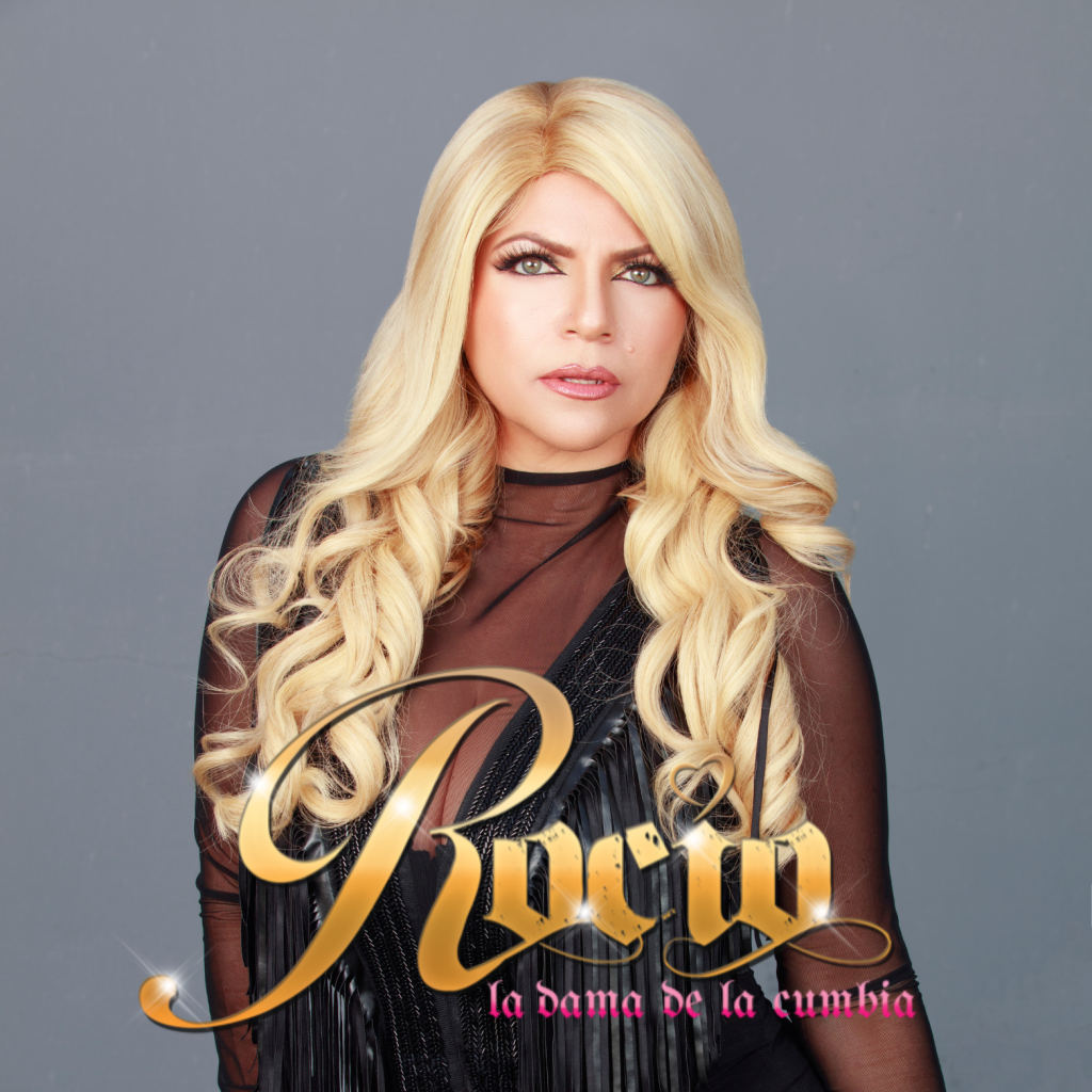 A woman with long blonde hair wearing a black dress with gold lettering that reads 'Rucia, la dama de la cumbia' in Healdsburg, California.