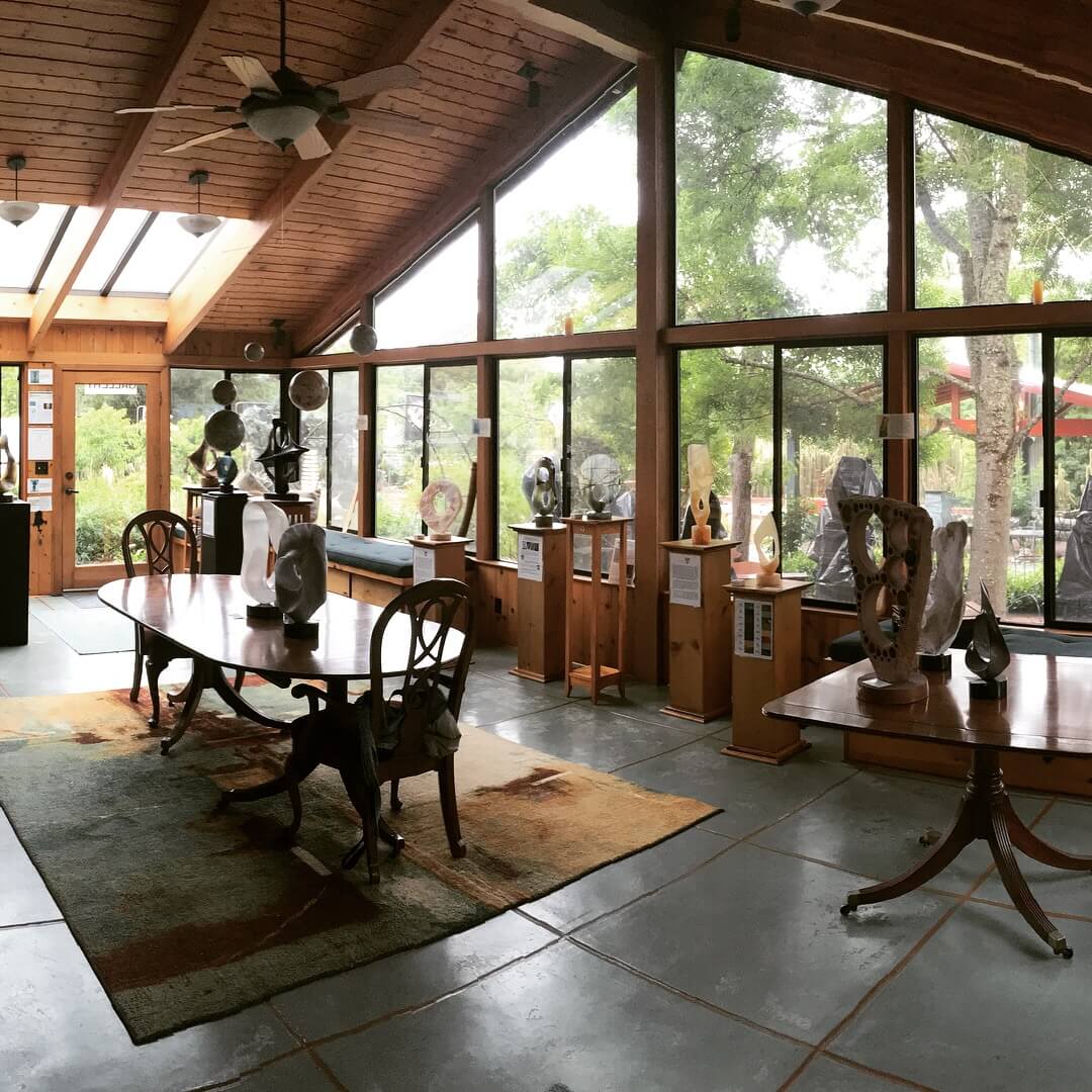 T Barny Gallery and Sculpture Gardens A spacious room with high wooden ceilings and large windows showcasing a variety of sculptures and artworks in Healdsburg, California.