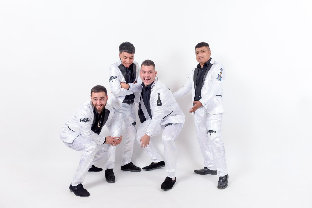 Four men dressed in matching white suits with black accents pose together, smiling and striking dynamic poses in Healdsburg, California.