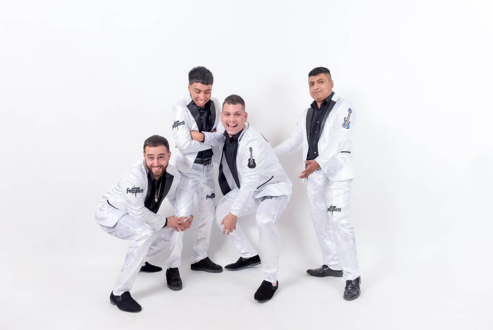 Four men dressed in matching white suits with black accents pose together, smiling and striking dynamic poses in Healdsburg, California.